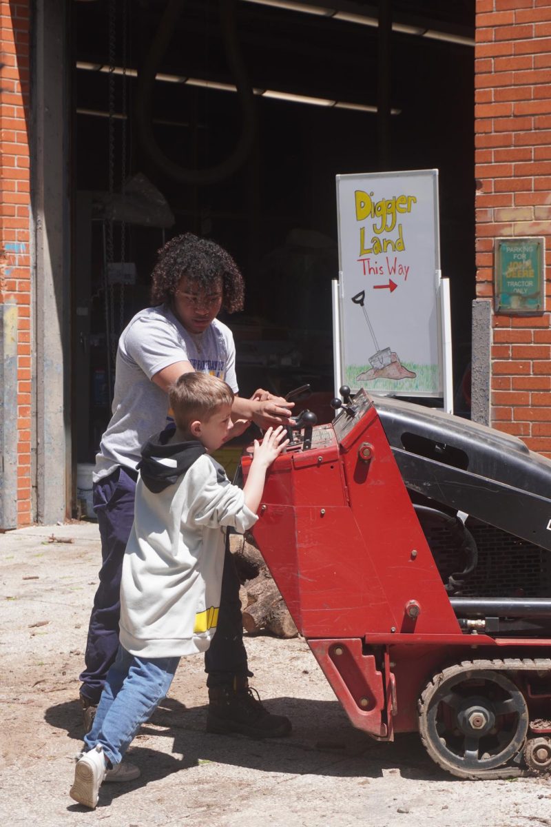 10th-grade Horticulture major student showing a kid how to use a Toro Dingo